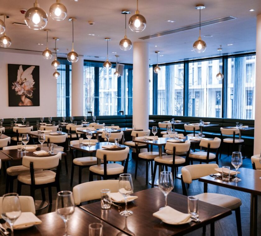 The image depicts the restaurant seating area. Chairs and tables set for dining